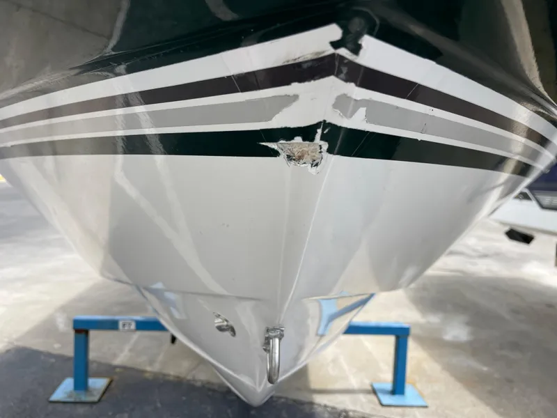 Slide: The Image of 1995 Four Winns 240 Horizon boat with visible hull damage on a stand. - 27