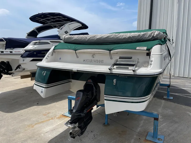 Slide: The Image of 1995 Four Winns 240 Horizon boat on stand, green and white exterior, docked near other boats. - 3