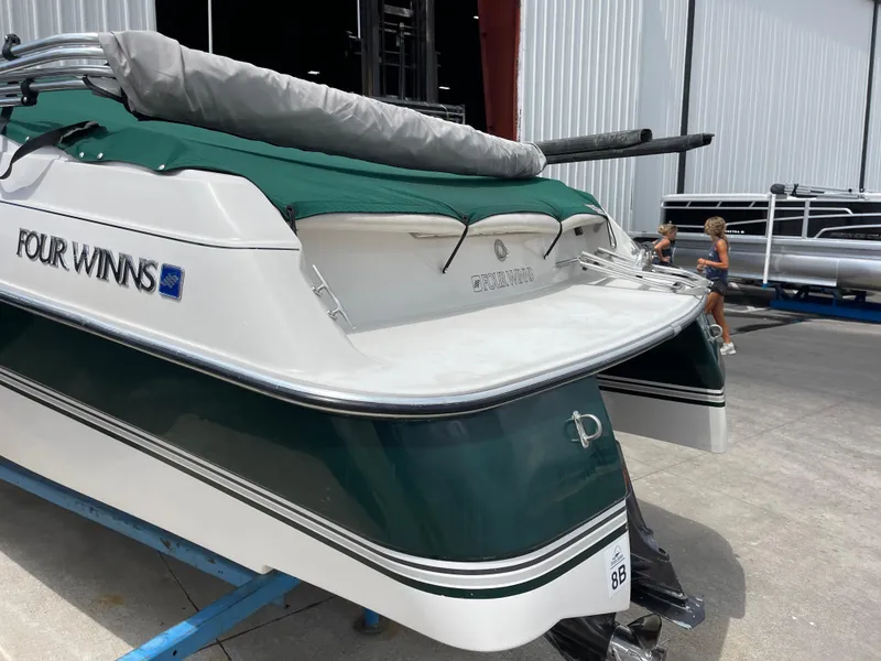 Slide: The Image of 1995 Four Winns 240 Horizon boat with green cover, docked near a warehouse. - 4
