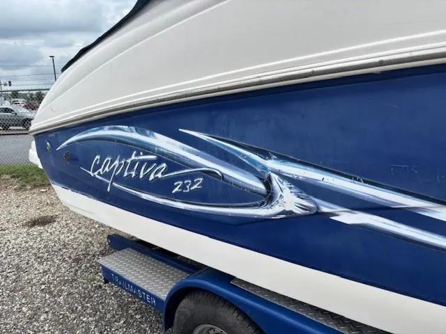 Slide: The Image of 2006 Rinker 232 Captiva Bowrider boat with blue and white design on trailer. - 2