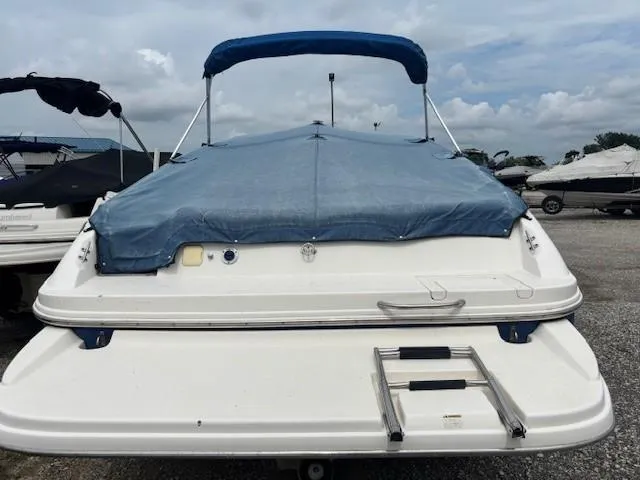 Slide: The Image of 2006 Rinker 232 Captiva Bowrider with blue cover, parked on gravel lot. - 22