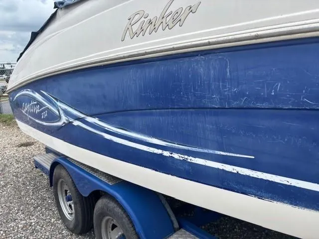 Slide: The Image of 2006 Rinker 232 Captiva Bowrider boat on trailer, showing blue and white exterior. - 28