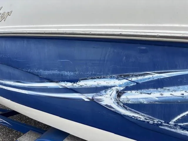Slide: The Image of 2006 Rinker 232 Captiva Bowrider with visible hull scratches and blue design. - 33
