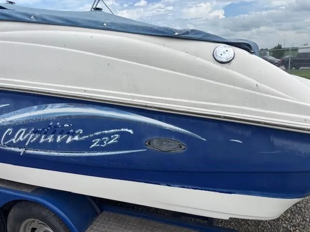 Slide: The Image of 2006 Rinker 232 Captiva Bowrider boat with blue and white exterior on a trailer. - 35