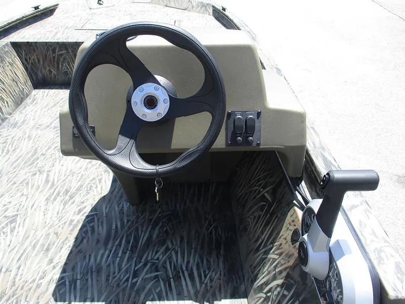Slide: The Image of 2026 Tracker Grizzly 1648 SC boat steering console with camo design and control panel. - 16