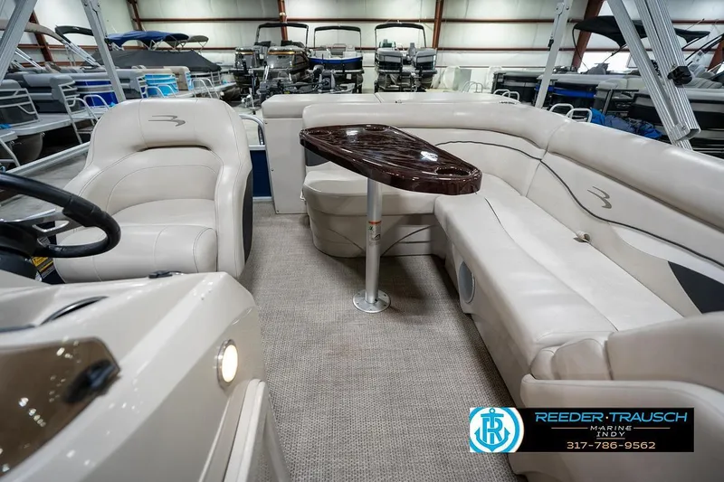 Slide: The Image of 2019 Bennington 18 SLV pontoon boat interior with beige seating and wooden table. - 17
