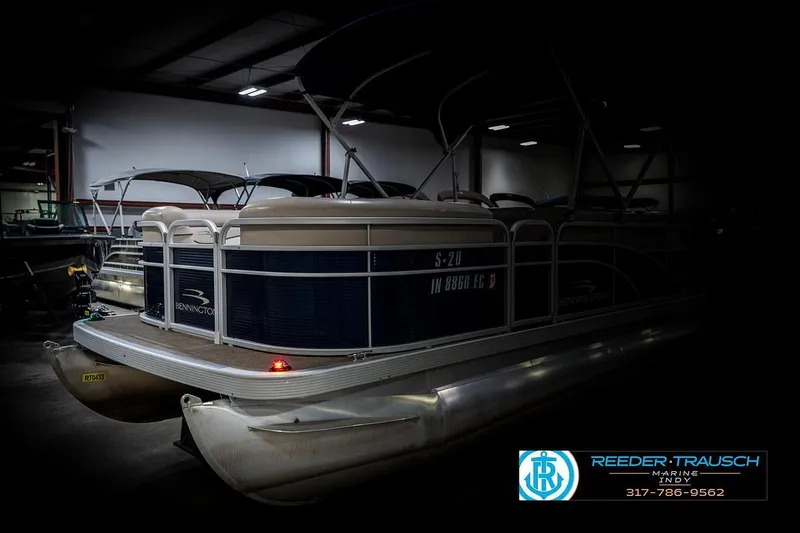Slide: The Image of 2019 Bennington 18 SLV pontoon boat in a dimly lit showroom. - 4
