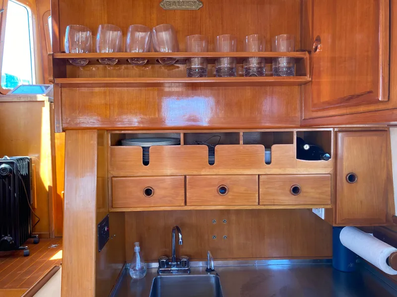 Slide: The Image of 1986 Transpacific Marine Eagle yacht galley with wooden cabinetry and glassware storage. - 10