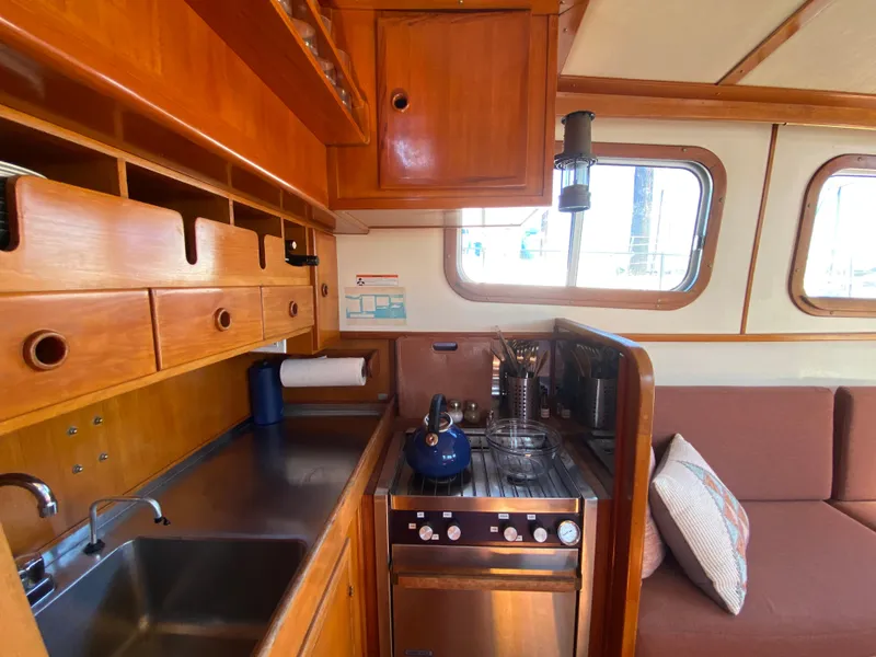 Slide: The Image of 1986 Transpacific Marine Eagle yacht interior with wooden cabinetry, kitchen, and seating area. - 12