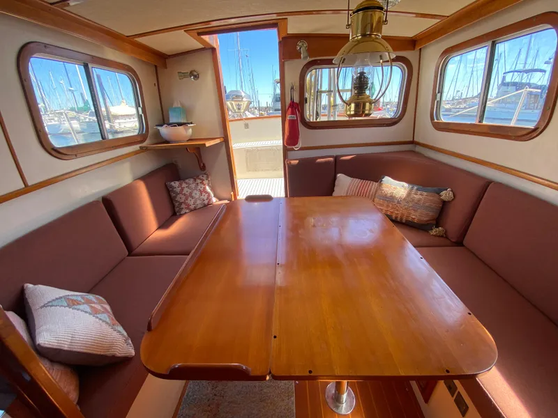 Slide: The Image of 1986 Transpacific Marine Eagle yacht interior with wooden table, cushioned seating, and nautical decor. - 14