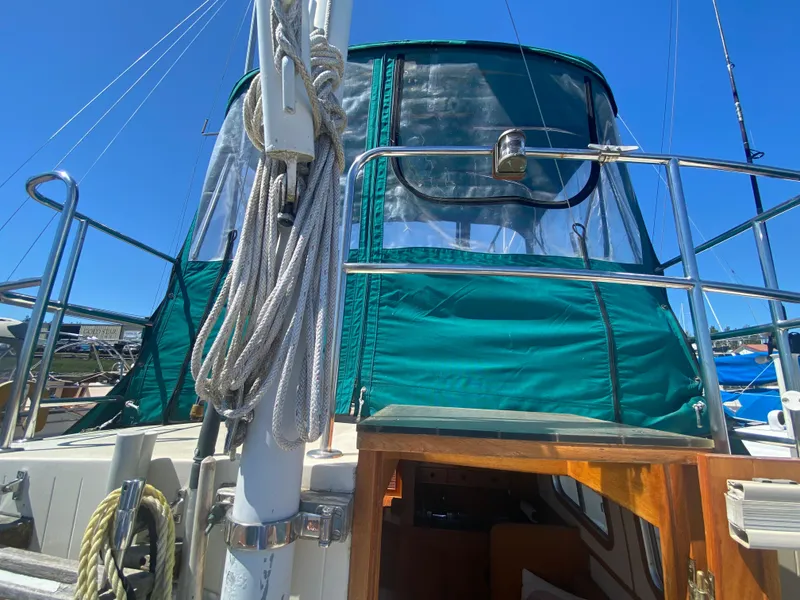 Slide: The Image of 1986 Transpacific Marine Eagle sailboat with green canopy and ropes, docked under clear blue sky. - 8