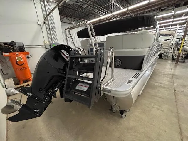 Slide: The Image of 2025 Harris Cruiser 230 CWDH pontoon boat in a warehouse, featuring a powerful outboard motor. - 19