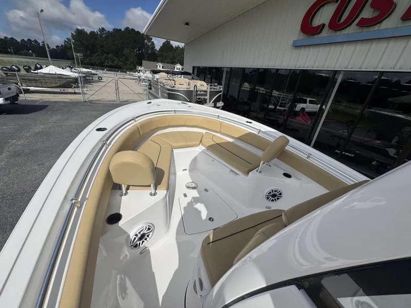 Slide: The Image of 2026 Sportsman Heritage 231 Center Console boat with beige seating, docked near a showroom. - 22
