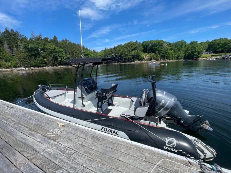 The Image of 2022 Zodiac Open 7 boat docked on a serene lake with lush green trees. - 0