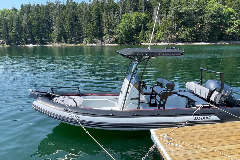 Slide: The Image of 2022 Zodiac Open 7 boat docked on a serene lake with forested background. - 11