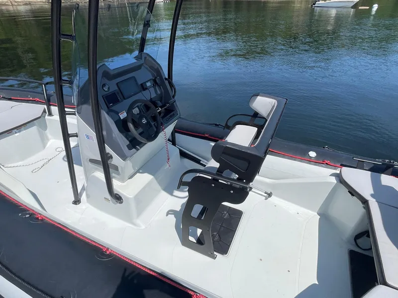 Slide: The Image of 2022 Zodiac Open 7 boat interior with steering console and seating, docked on calm water. - 15