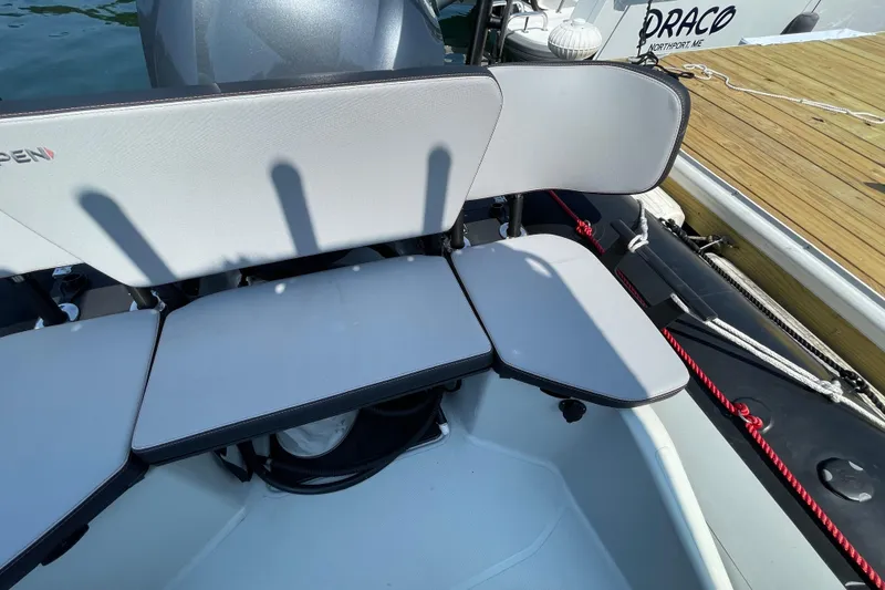 Slide: The Image of 2022 Zodiac Open 7 boat seating area with gray cushions and dock in background. - 28