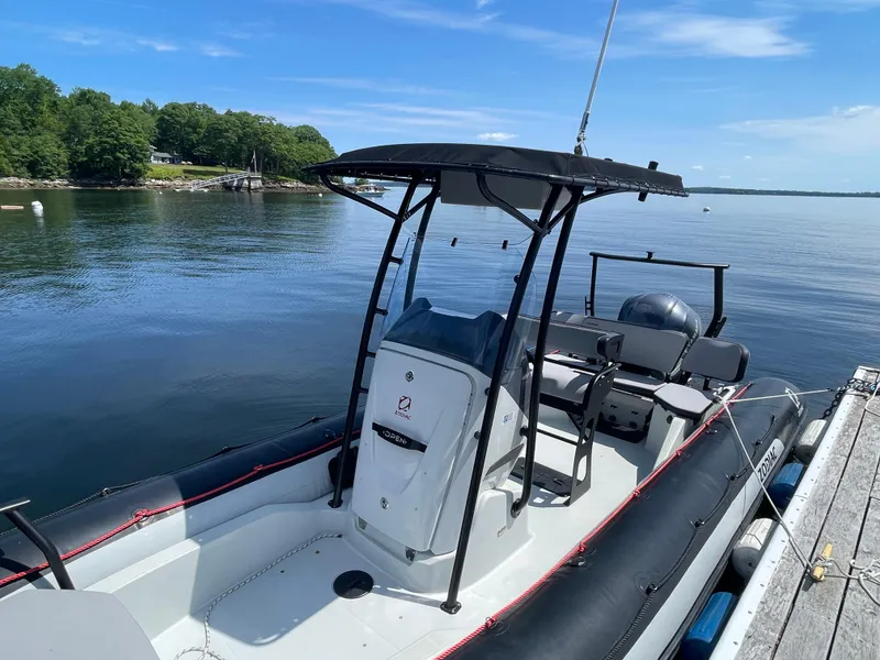 Slide: The Image of 2022 Zodiac Open 7 boat docked on calm water with lush green shoreline. - 5