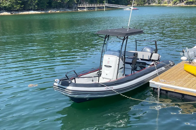 Slide: The Image of 2022 Zodiac Open 7 boat docked on calm water, surrounded by lush greenery. - 9