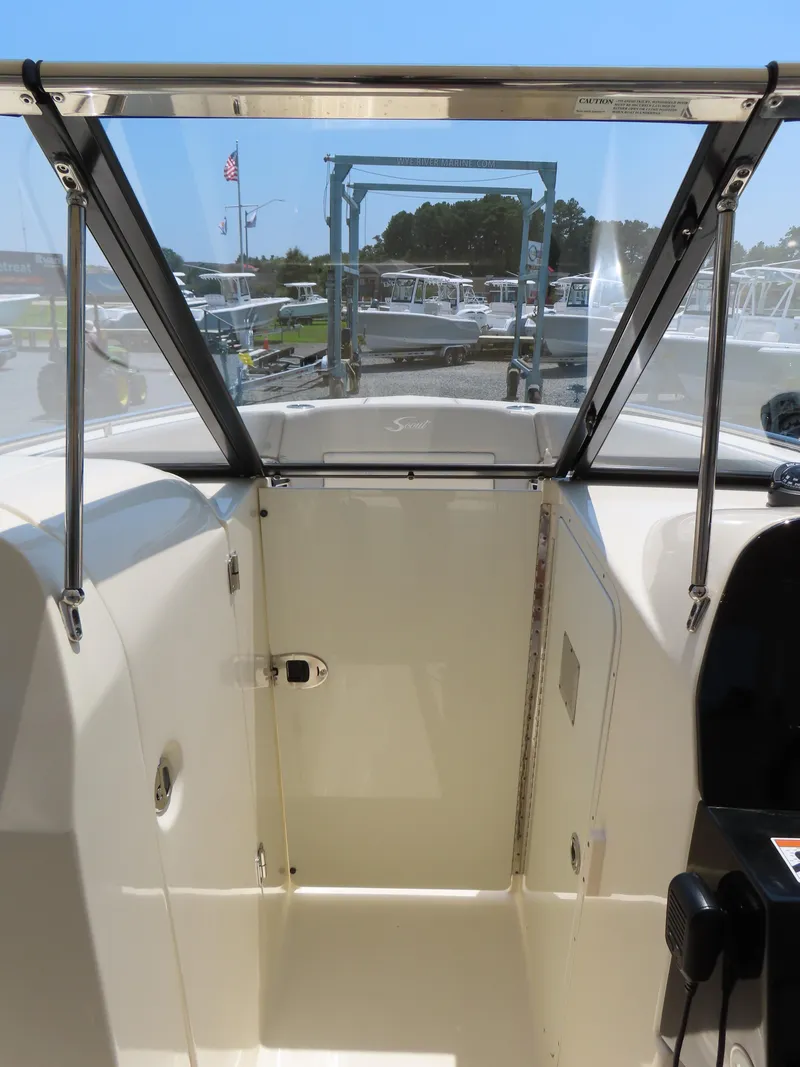 Slide: The Image of 2022 Scout 255 Dorado boat interior with open windshield and visible dock background. - 32