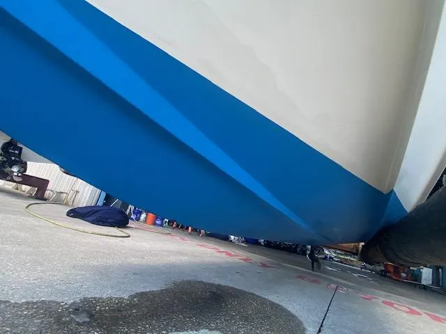 Slide: The Image of 1989 Boston Whaler 20 Outrage boat hull with blue and white paint, docked on concrete. - 24