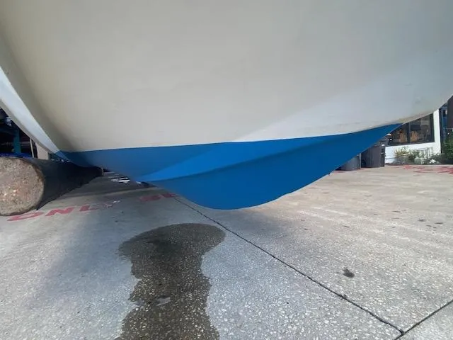 Slide: The Image of 1989 Boston Whaler 20 Outrage boat hull with blue paint, displayed on concrete surface. - 25