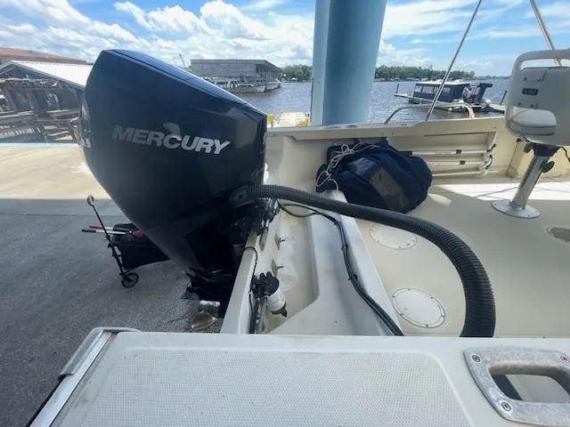 Slide: The Image of 1989 Boston Whaler 21 Outrage boat docked by a river under a clear blue sky. - 5