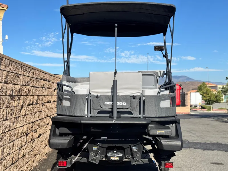 Slide: The Image of 2023 Sea-Doo Switch Sport 18 pontoon boat, rear view, parked outdoors. - 5