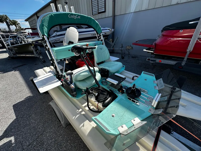 Slide: The Image of 2020 CraigCat CATCHIT boat with teal seating and controls, parked outdoors. - 5