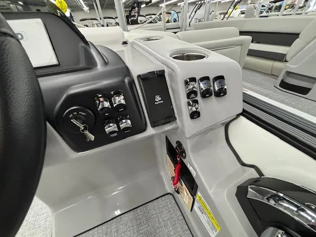 Slide: The Image of 2025 Harris Sunliner 230 boat dashboard with controls and cup holder. - 12