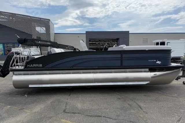 Slide: The Image of 2025 Harris Sunliner 230 pontoon boat parked outdoors under cloudy sky. - 3