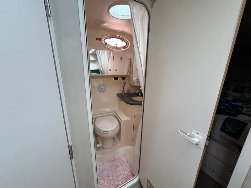 Slide: The Image of 1997 Sea Ray 370 Aft Cabin bathroom with toilet, sink, and porthole window. - 37