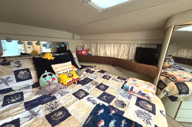 Slide: The Image of Cozy cabin interior of 1997 Sea Ray 370 Aft, featuring nautical-themed bedding and plush toys. - 46