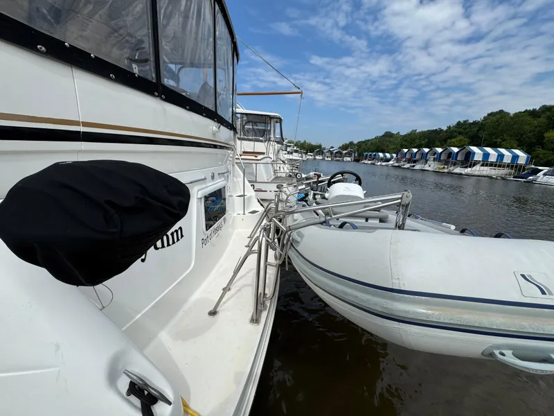 Slide: The Image of 1997 Sea Ray 370 Aft Cabin yacht docked with inflatable boat, under a partly cloudy sky. - 5