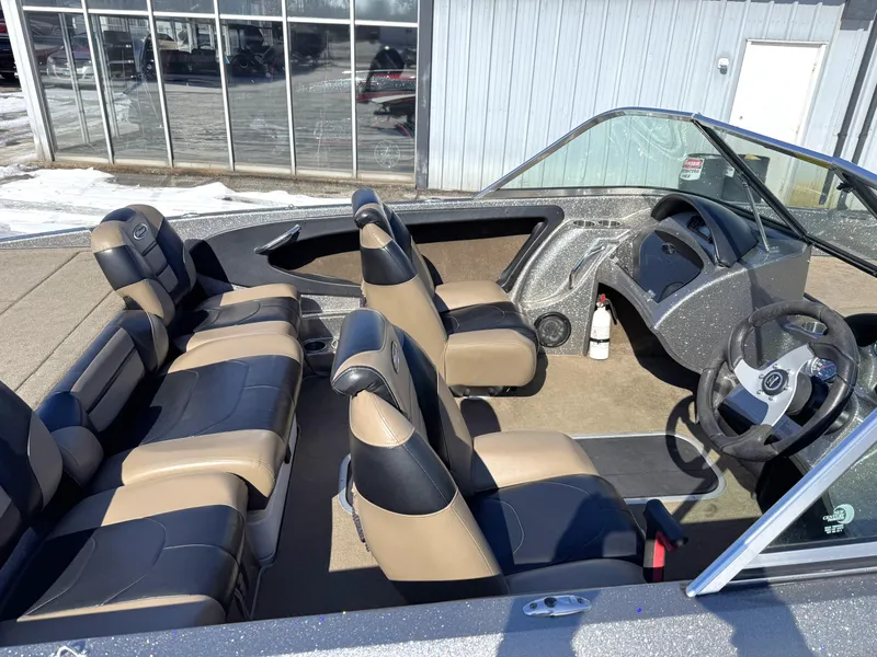 Slide: The Image of 2013 Triton 190 SE boat interior with beige and black seating, steering wheel, and dashboard. - 2