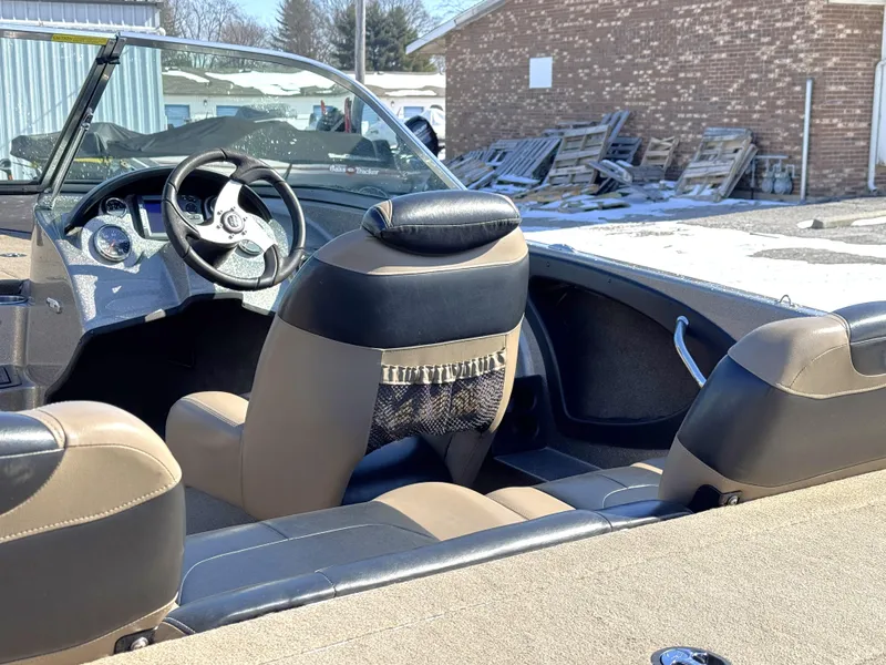 Slide: The Image of 2013 Triton 190 SE boat interior with steering wheel and seating, parked outdoors. - 5