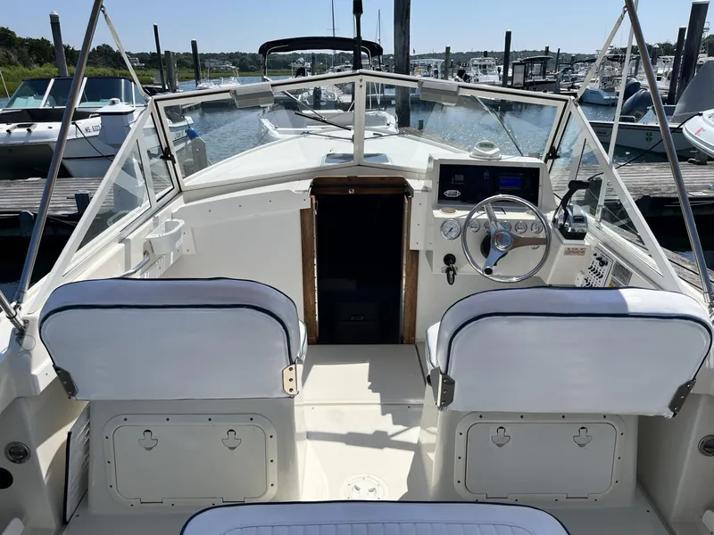 Slide: The Image of 2002 Limestone 24 Cuddy Cabin boat interior with steering wheel and seating at marina. - 13