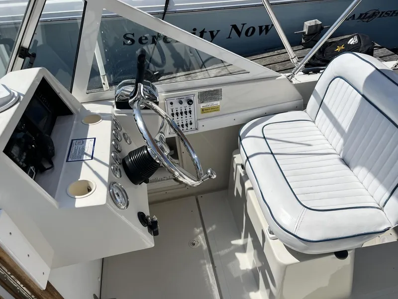 Slide: The Image of 2002 Limestone 24 Cuddy Cabin boat interior with steering wheel and white seating. - 15