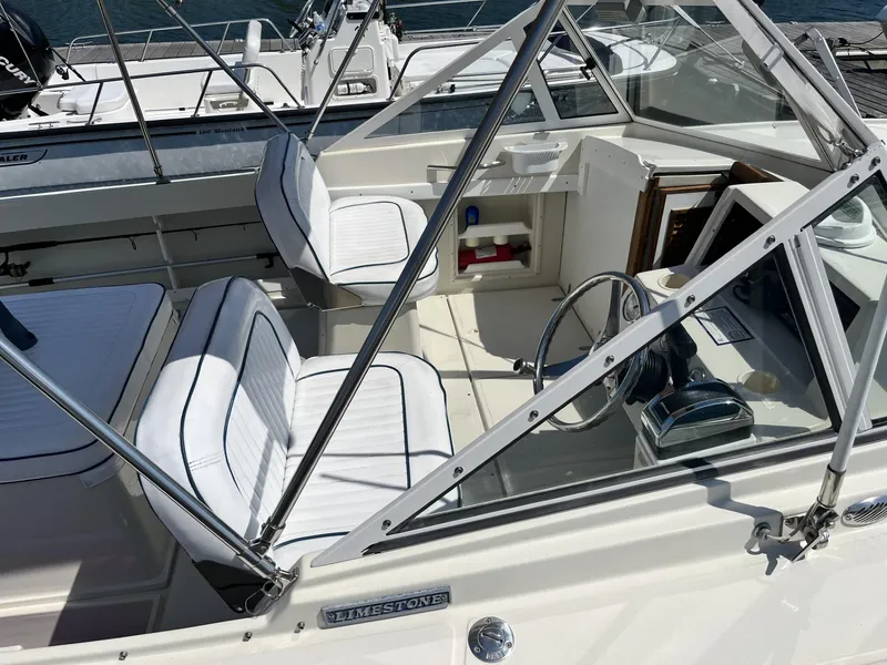 Slide: The Image of 2002 Limestone 24 Cuddy Cabin boat interior with white seating and steering wheel. - 16