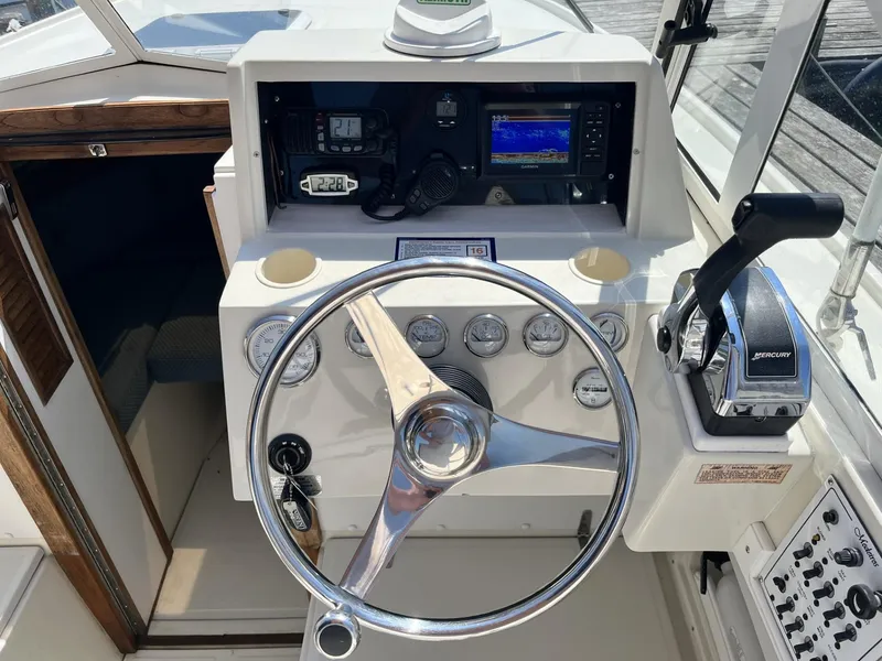 Slide: The Image of 2002 Limestone 24 Cuddy Cabin boat helm with steering wheel and control panel. - 17