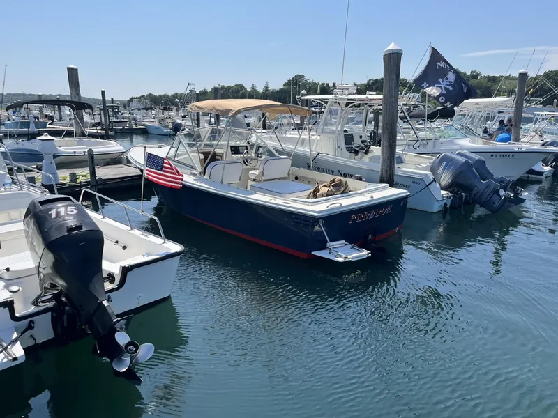 Slide: The Image of 2002 Limestone 24 Cuddy Cabin boat docked in a marina, featuring an American flag. - 2