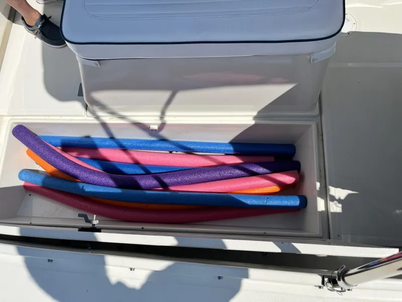 Slide: The Image of Storage compartment with colorful pool noodles on a 2002 Limestone 24 Cuddy Cabin boat. - 24