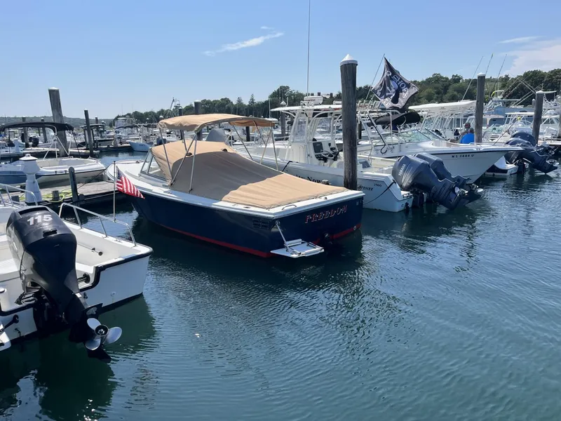 Slide: The Image of 2002 Limestone 24 Cuddy Cabin boat docked in a marina, featuring a tan canopy. - 3