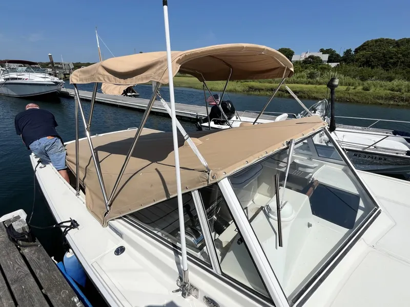 Slide: The Image of 2002 Limestone 24 Cuddy Cabin boat docked with beige canopy, clear sky background. - 8