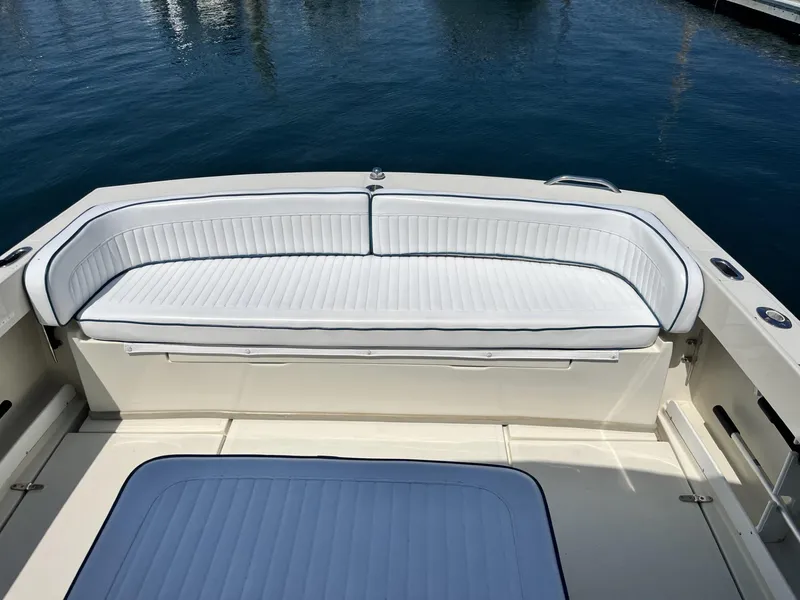 Slide: The Image of 2002 Limestone 24 Cuddy Cabin boat with white cushioned seating, docked on calm water. - 9