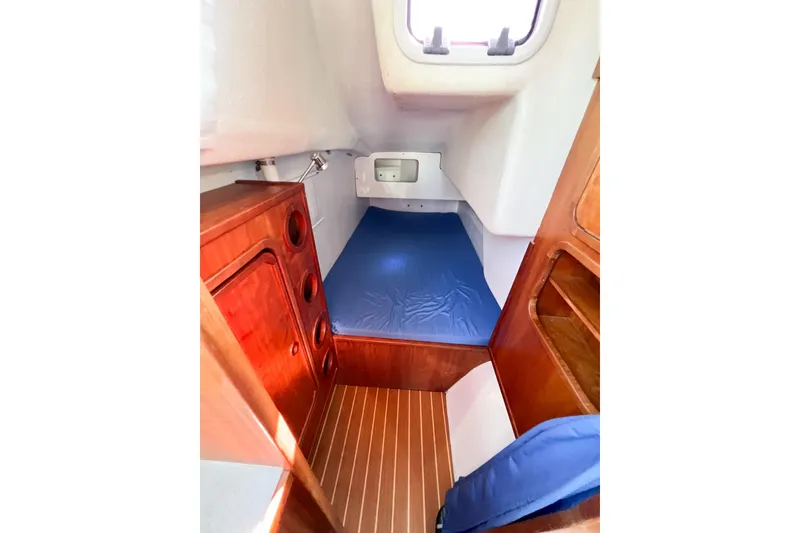Slide: The Image of 2012 TomCat 9.70 s cabin interior with wooden finish and blue bedding. - 31