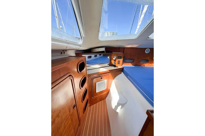 Slide: The Image of Interior of 2012 TomCat 9.70 s sailboat with wooden cabinetry and blue seating. - 37
