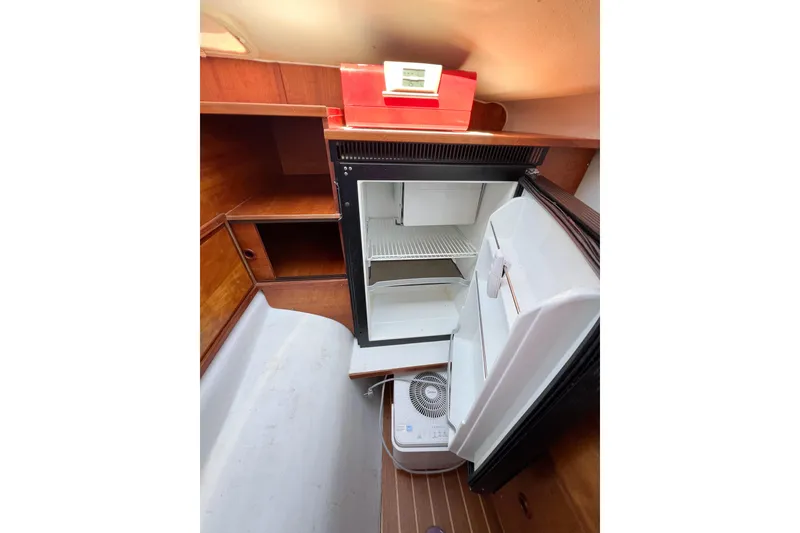 Slide: The Image of Compact refrigerator in 2012 TomCat 9.70 s boat interior, featuring wooden cabinetry. - 46