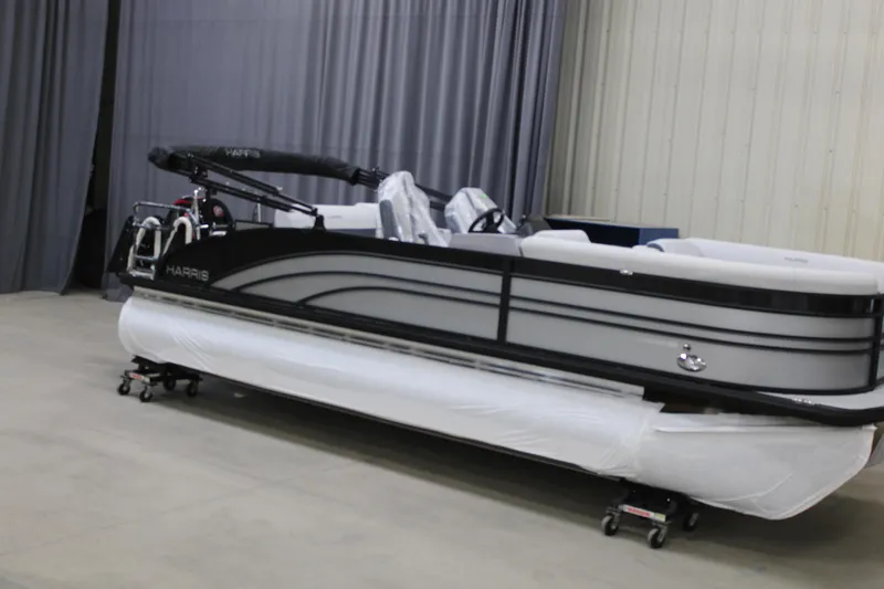 The Image of 2025 Harris Sunliner 230 pontoon boat in showroom, sleek design, black and white color scheme. - 1