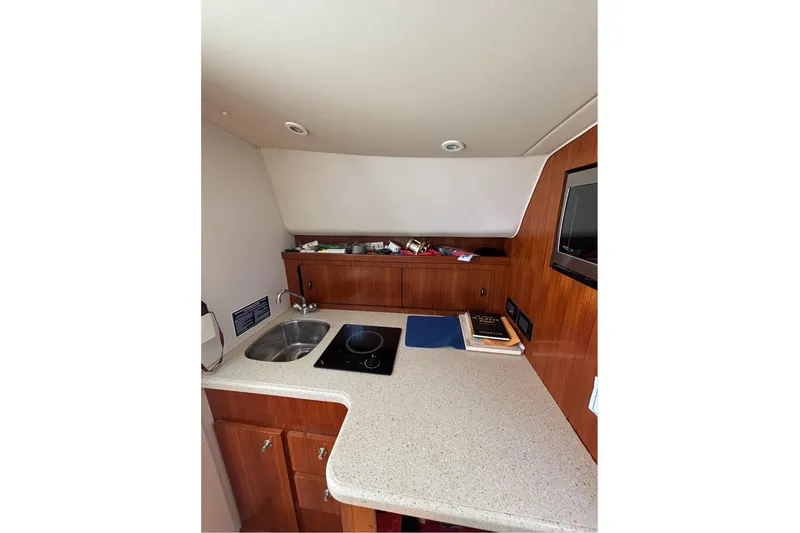 Slide: The Image of 2006 Tiara Yachts 2900 interior kitchen with sink, stove, and wooden cabinetry. - 18
